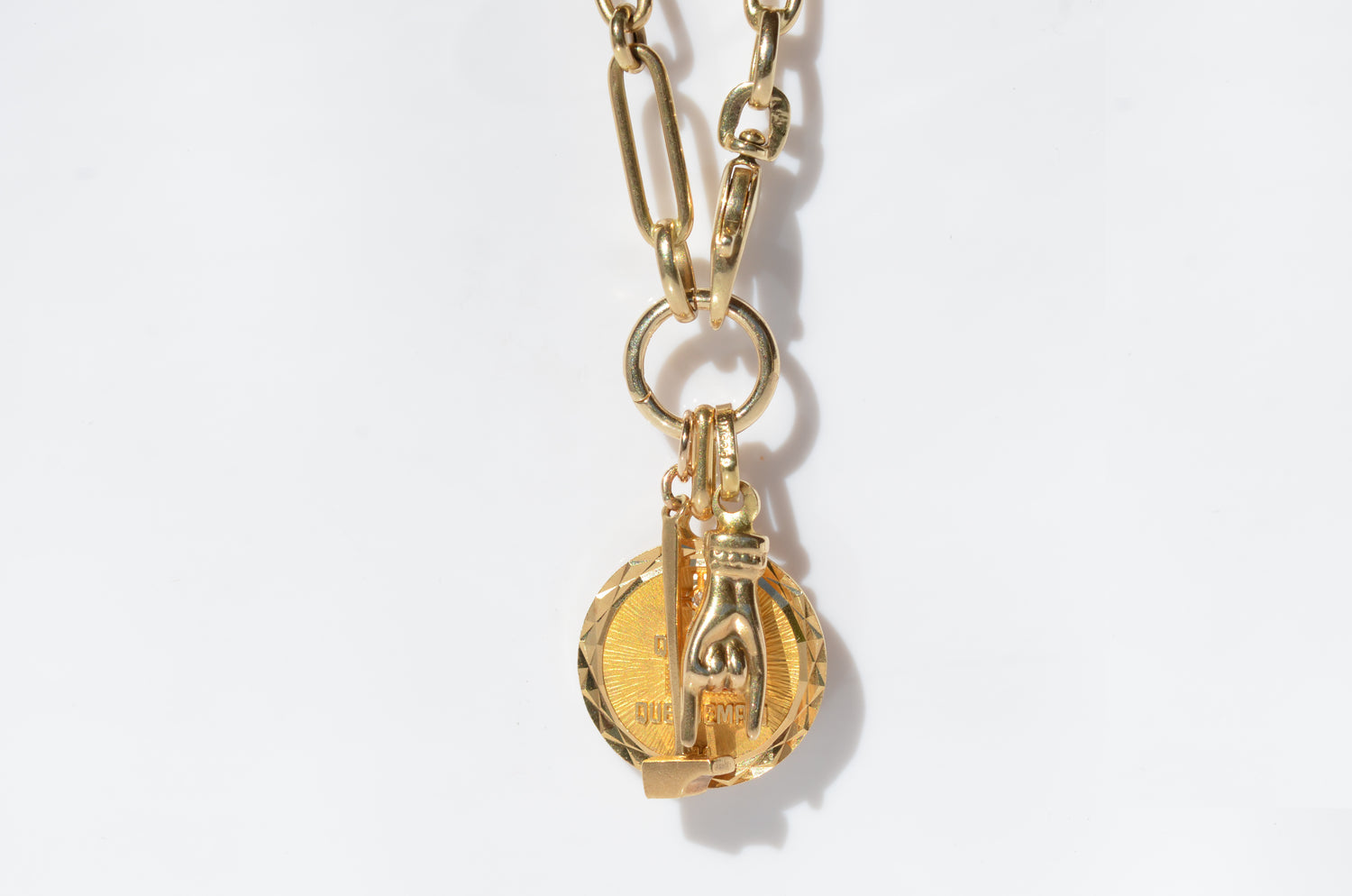 a contemporary chain and charm ring hold a trio of vintage pendants: an Egyptian hammer, a French love token, and an Italian mano cornuto