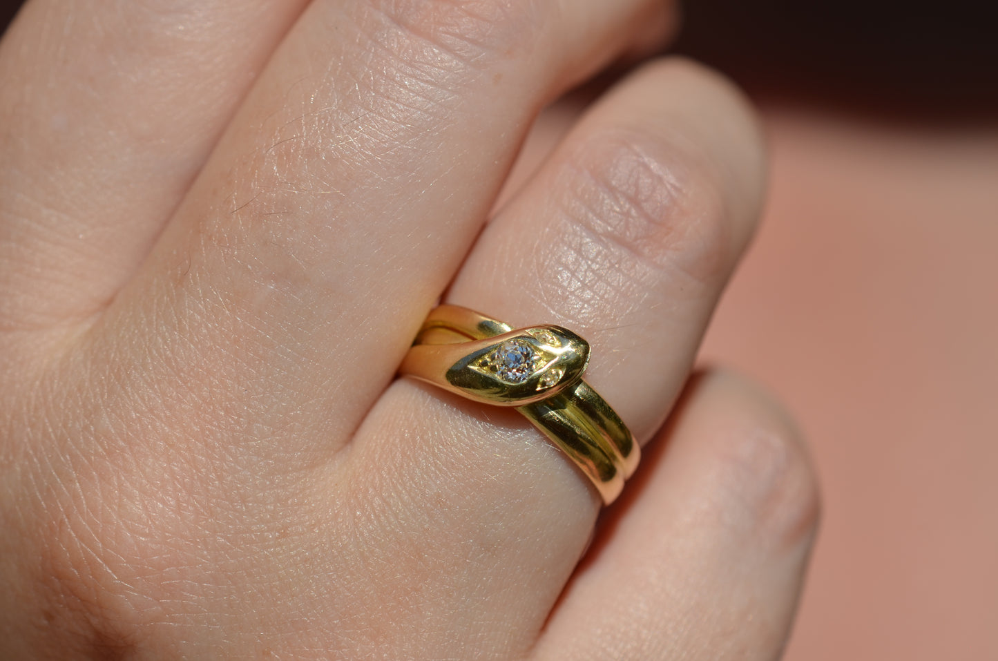 Macro of Victorian yellow gold snake ring with diamond head and eyes shown on the right ring finger of a Caucasian model to demonstrate scale while worn.