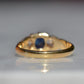 A Victorian ring in yellow gold with swirling shoulders and a central vivid blue sapphire flanked by a pair of old mine cut diamonds, photographed from the back, highlighting the very good condition of the back of the band.
