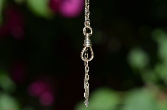 A closely cropped photo of the bracelet suspended and dangling, focusing on the dog clip clasp. 