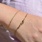 A closely cropped view of the bracelet on a Caucasian model's wrist. She is wearing several other gold bracelets and has a small tattoo of the "Space Coyote" character from The Simpsons.