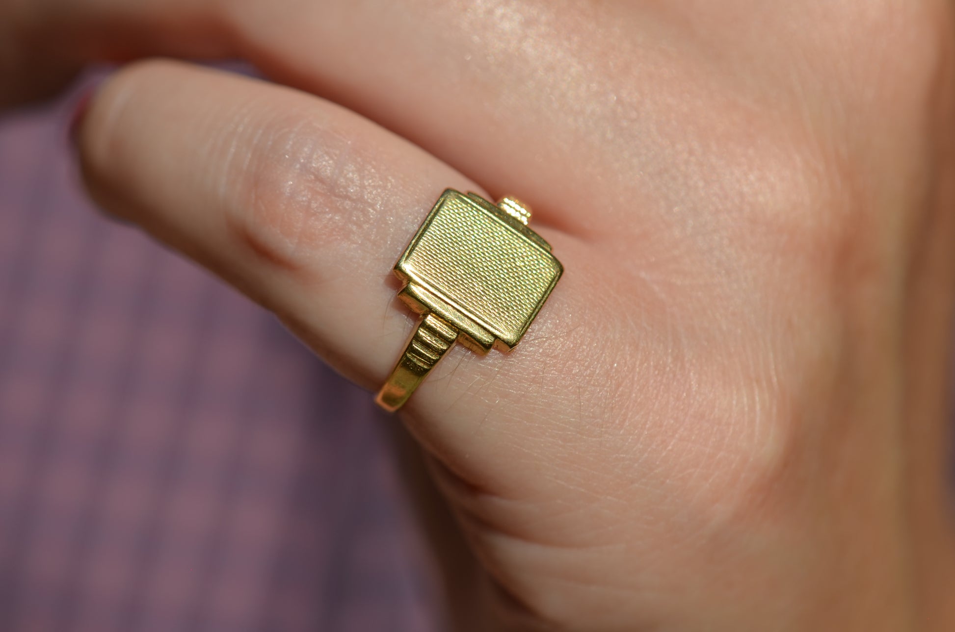 A closely cropped view of the ring on a Caucasian model's left pinky finger.