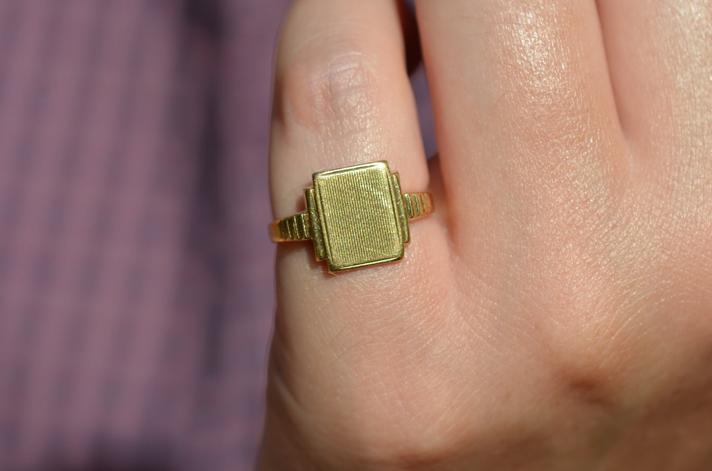 A closely cropped view of the ring on a Caucasian model's left pinky finger.