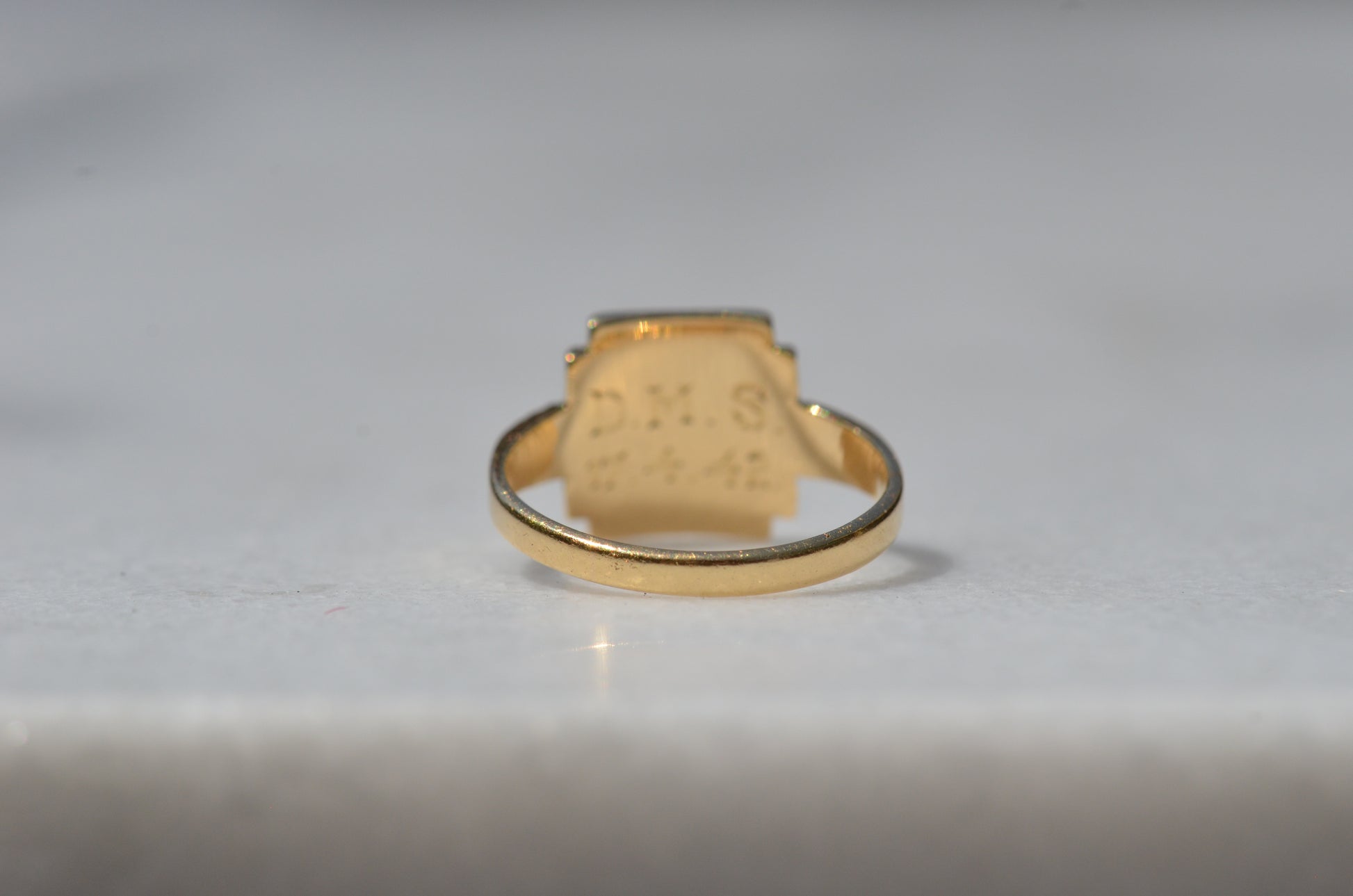 The ring is viewed from the back, with the band in focus, and minor evidence of past resizing in the form of a small patch of pitting on a solder seam.