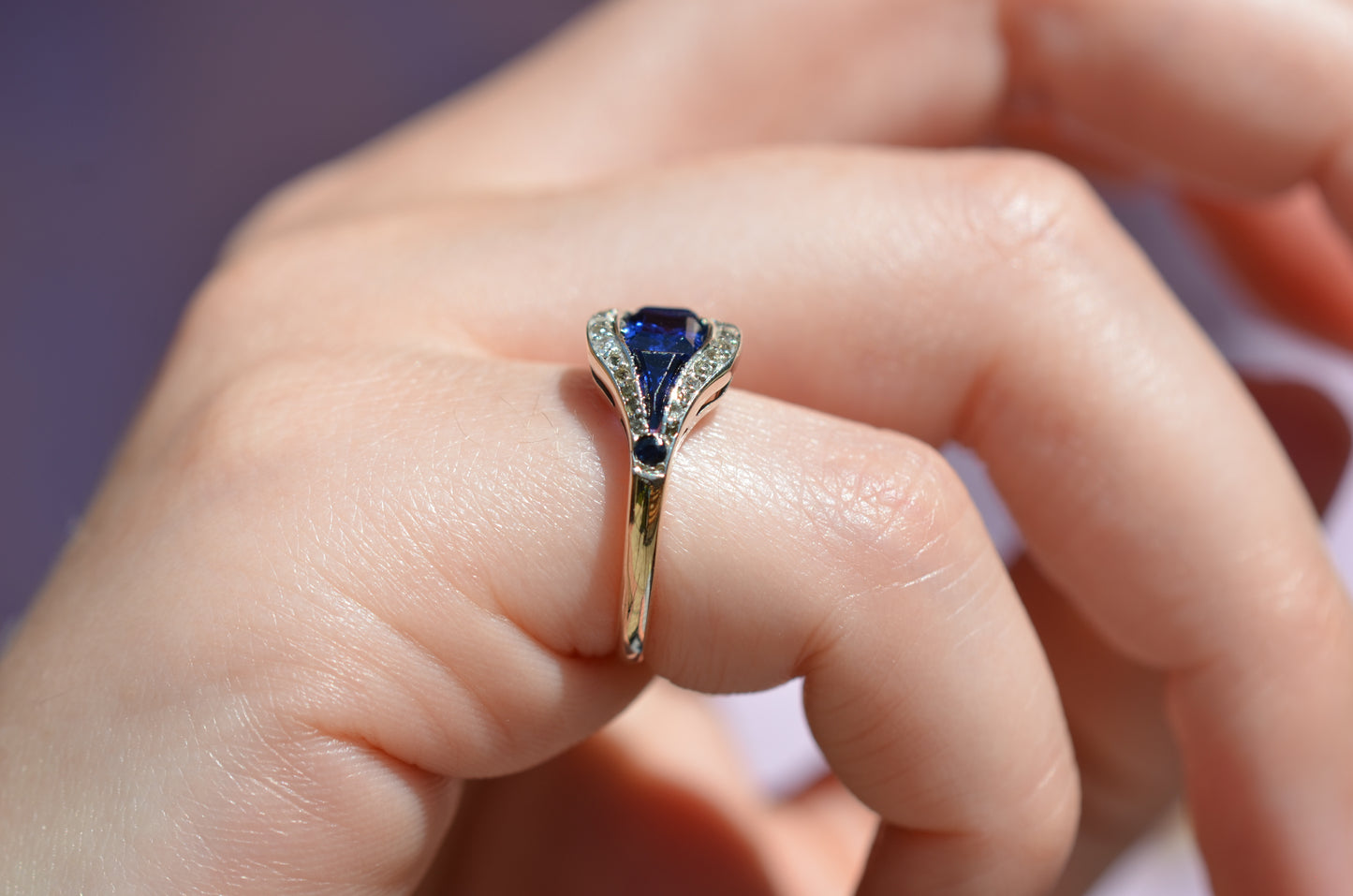 A closely cropped macro of the ring, vibrant in bright daylight, on the right pinky finger of a Caucasian model. The ring is shown from the side to highlight the medium-low rise off the finger.