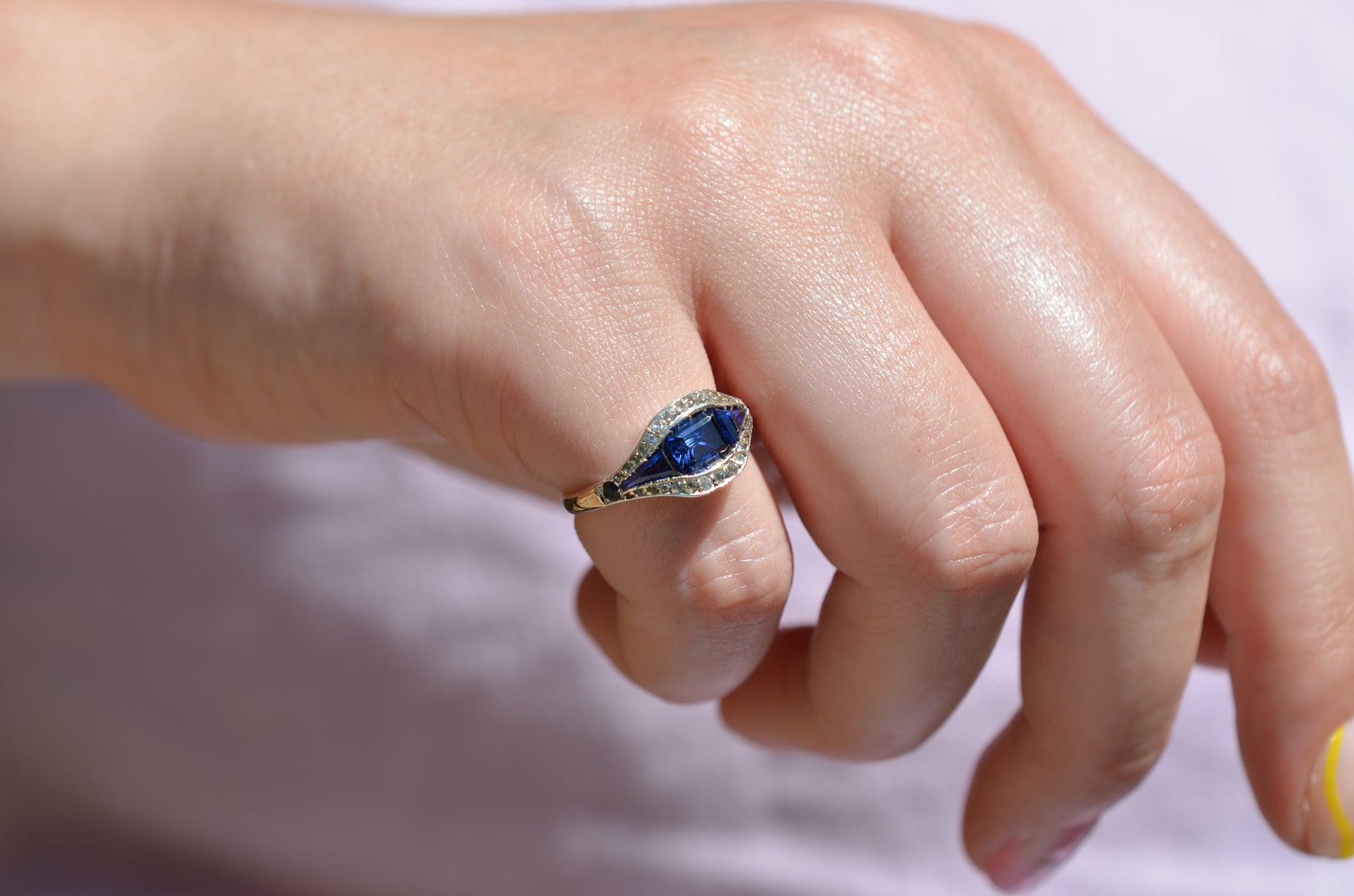 A closely cropped macro of the ring, vibrant in bright daylight, on the right pinky finger of a Caucasian model.