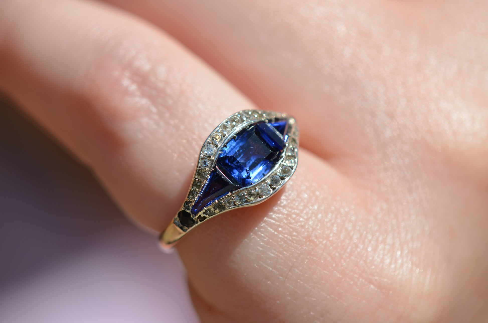 A closely cropped macro of the ring, vibrant in bright daylight, on the left pinky finger of a Caucasian model.