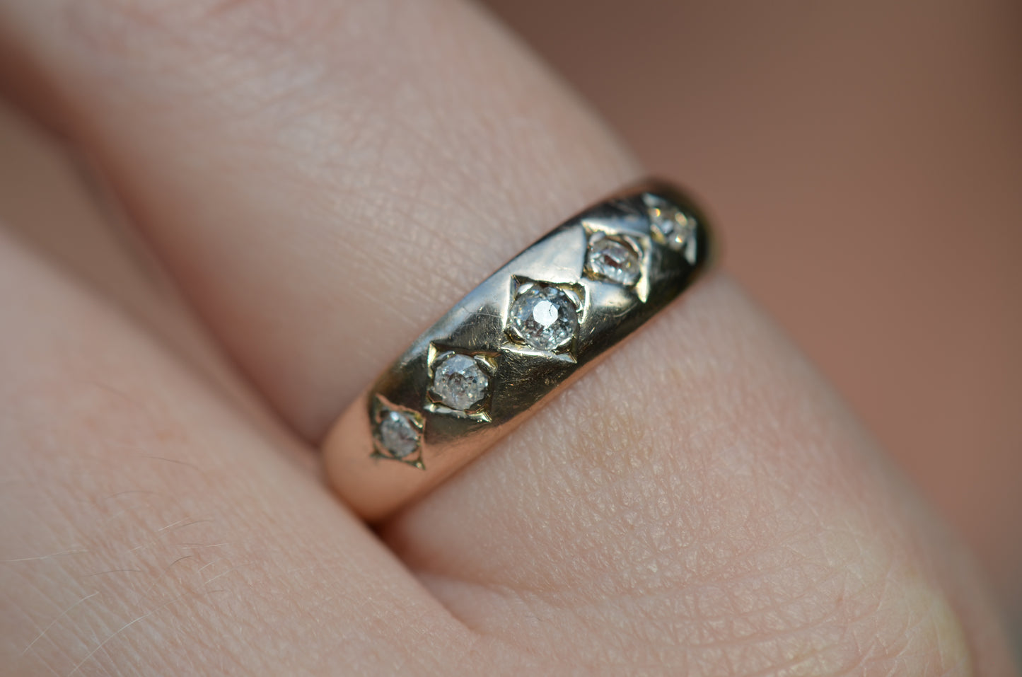 A tightly cropped macro of the ring on the left pointer finger of a Caucasian model. With the light reflecting of the centre stone's table, it's possible to see the surface-reaching edge of a small fracture.