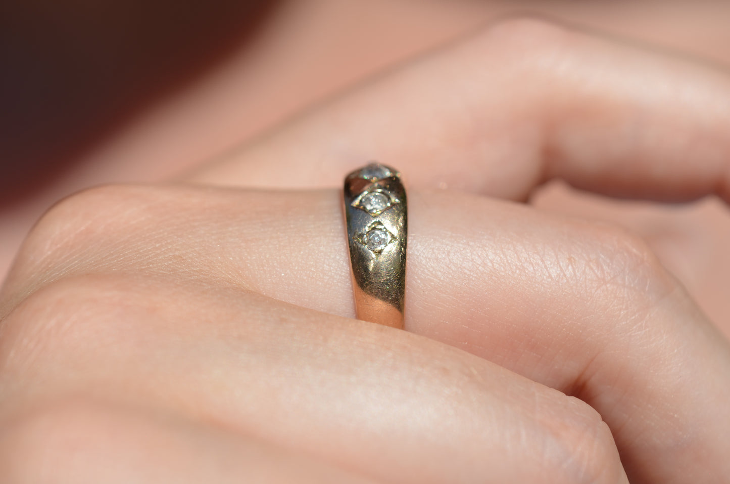 A tightly cropped macro of the ring on the right middle finger of a Caucasian model. The ring is shown from the side, highlighting the very low rise off the finger.