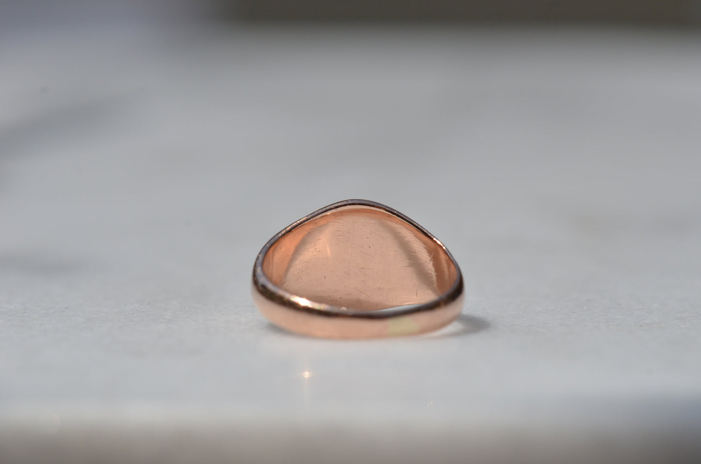 The back of the ring is shown with the back of the head in focus, showing smooth worn gold.