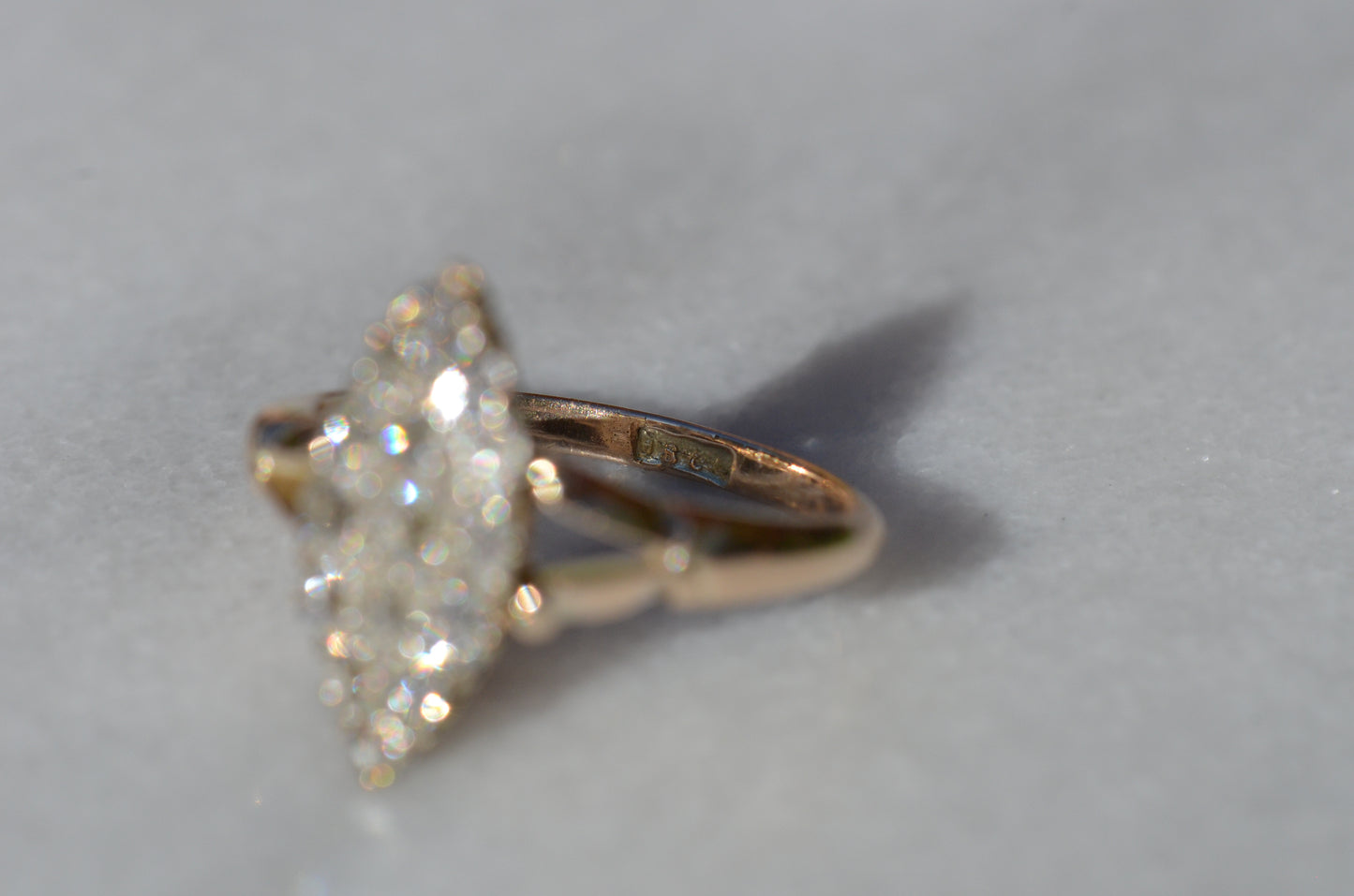 The closely cropped macro of this Victorian diamond navette ring is photographed looking into the band at a purity stamp that reads 18k, though the gold tests as 14k.