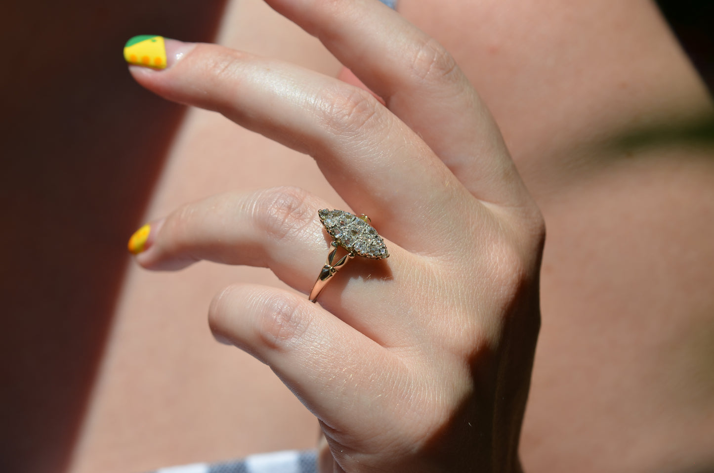 A medium-close photo of the antique ring on a Caucasian model's left ring finger to show scale, photographed in natural light that dazzles on the diamonds.