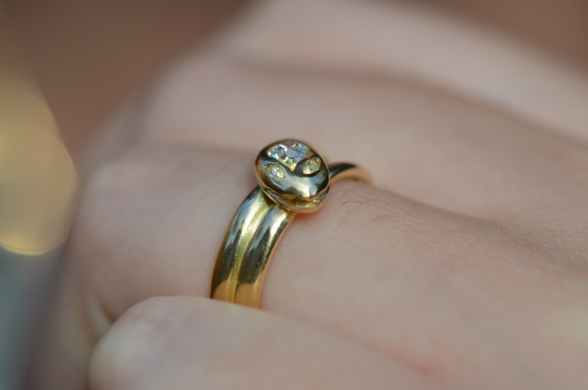 Macro of Victorian yellow gold snake ring with diamond head and eyes shown on the left ring finger of a Caucasian model to demonstrate scale while worn.