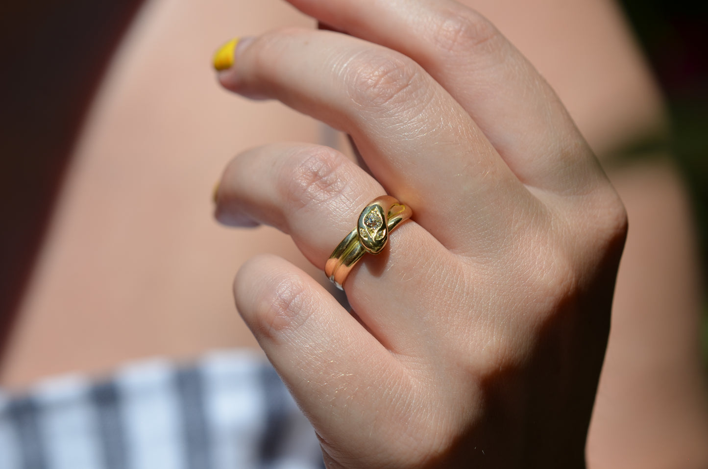 Medium-close view of Victorian yellow gold snake ring with diamond head and eyes shown on the left ring finger of a Caucasian model to demonstrate scale while worn.