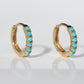 the pair of earrings is displayed, slightly at an angle so that the stones and settings can be clearly seen, on a stark white background