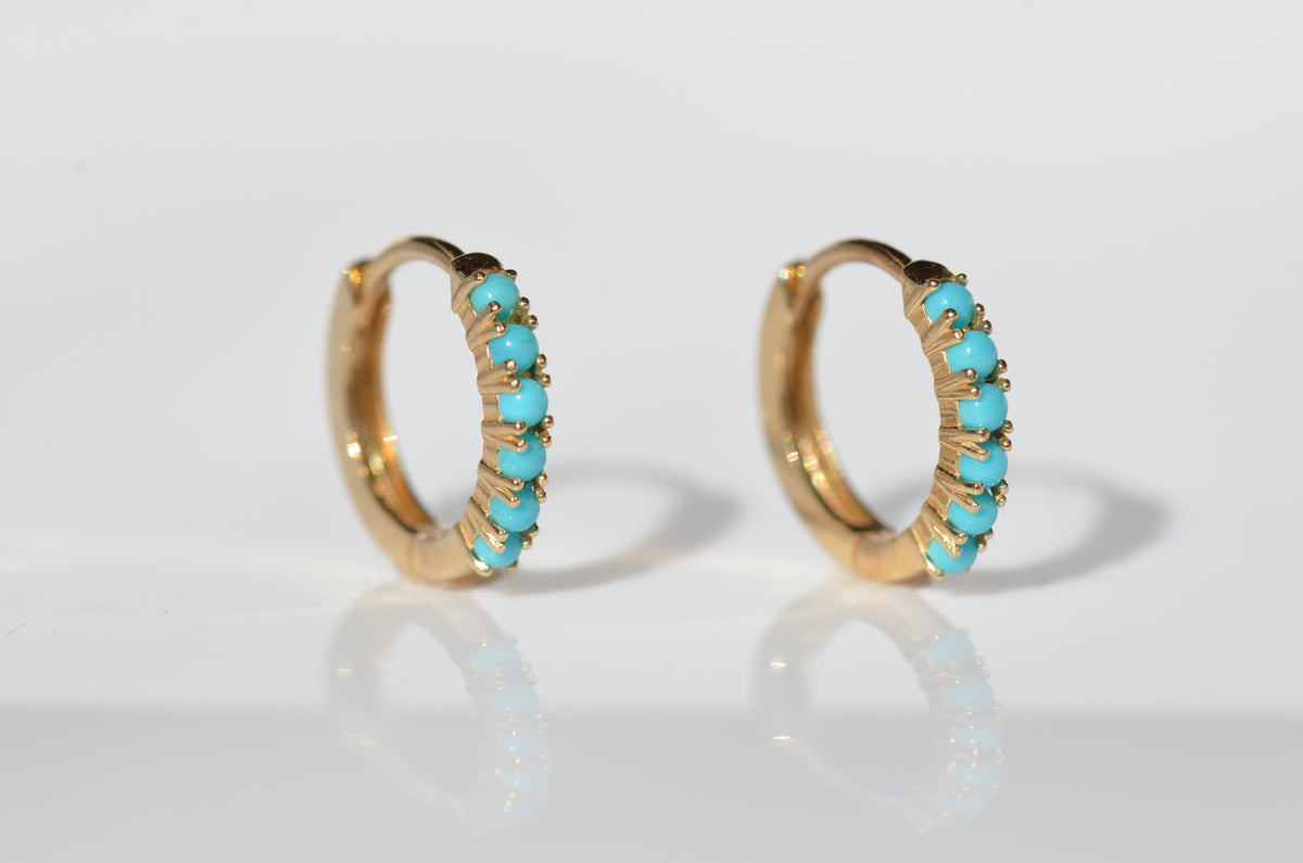 the pair of earrings is displayed, slightly at an angle so that the stones and settings can be clearly seen, on a stark white background