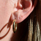 in direct sunlight, the hoop earrings are shown on a caucasian model's first piercing to show scale. the fit is loose.