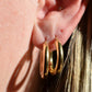 in direct sunlight, the hoop earrings are shown on a caucasian model's first and second lobe piercings to show scale. the fit is loose.