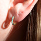 in direct sunlight, a single of the hoops is shown on the first lobe piercing of a caucasian model. the fit is moderately snug but not tight to the lobe.