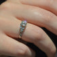 ring styled on the left ring finger  of a caucasian model. the photo has been taken in a mirror's reflection, with purple and orange flashes from the primary diamond.