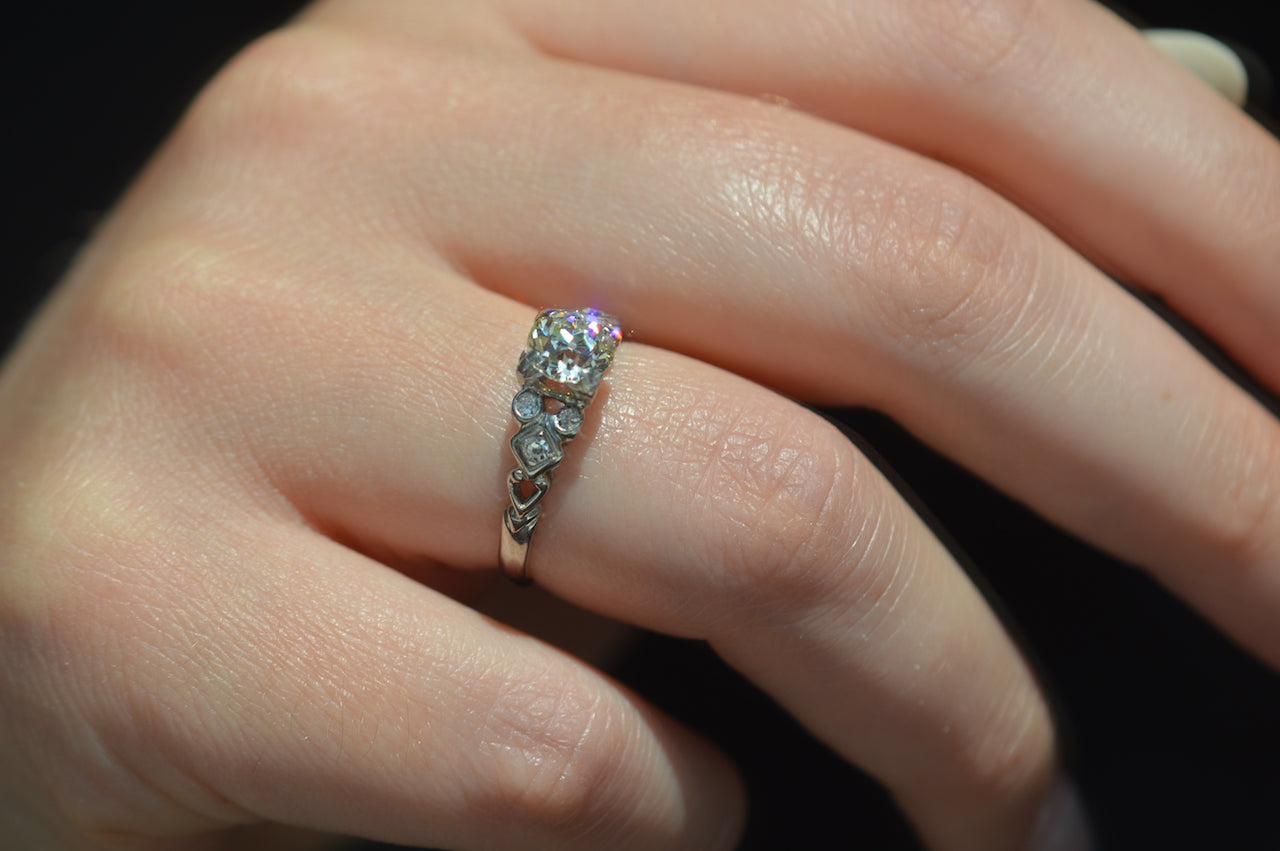 ring styled on the left ring finger  of a caucasian model. the photo has been taken in a mirror's reflection, with purple and orange flashes from the primary diamond.