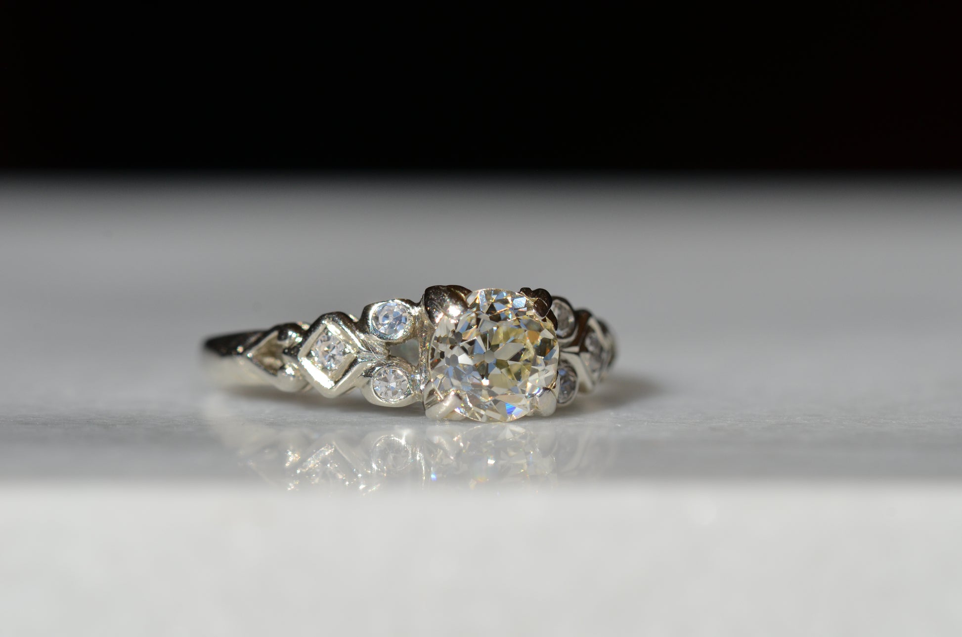 ring is tilted slightly to the right to showcase the clarity and depth of the antique old European cut diamond central to the piece. The left shoulder detail is also in focus.