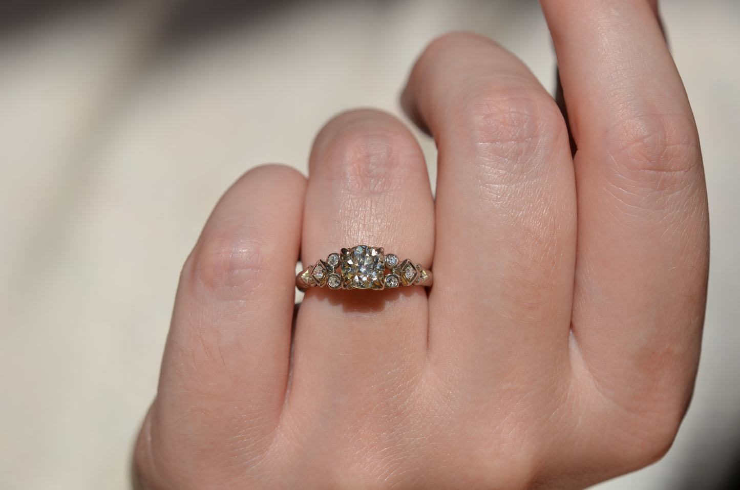 a direct-sun view of the ring head-on, worn on the left ring finger of a caucasian model. the ring appears warm in tone.