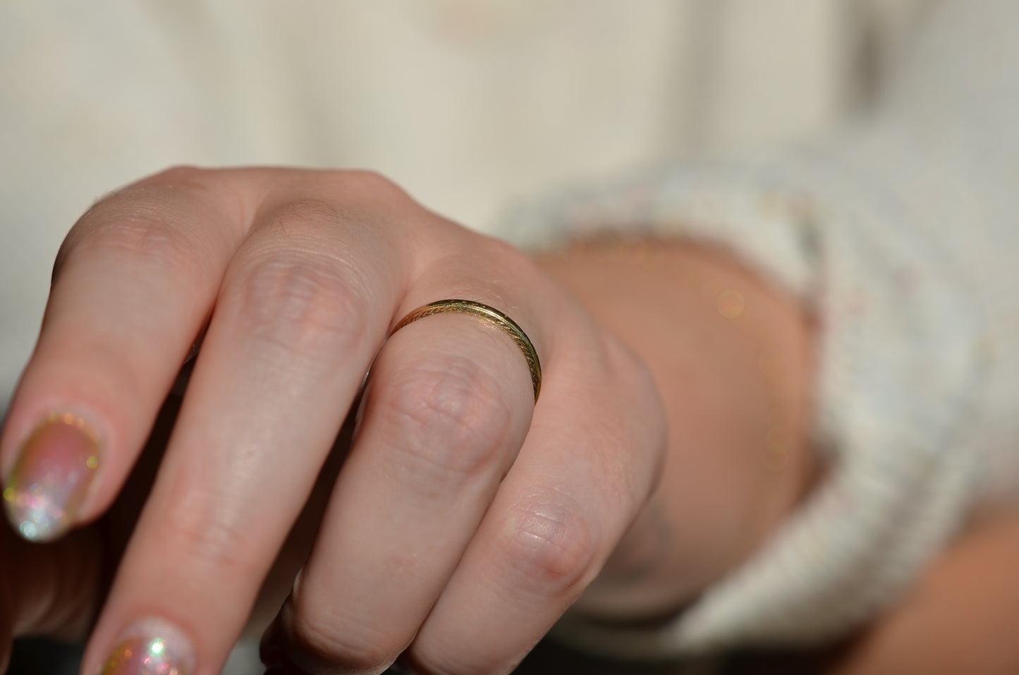 ring is modeled on the left ring finger of a caucasian model, with the hand angled so that the engraved sides of the band are visible.