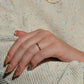 ring shown on the left ring finger of a caucasian model, shown in direct sunlight. image shows full hand and some body in order to help provide a sense of scale of the slim ring on the hand.
